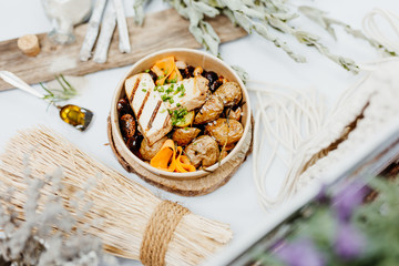 Vegetarian and vitamin-rich dish with tofu, beans and potatoes in eco-box, delivered by a delivery service, ordered online, decorated with bundles of straw on white wood, all in a Mediterranean style