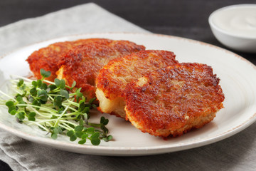 Potato pancakes with sour cream and dill on a wooden table