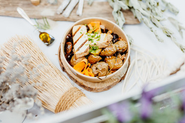 Vegetarian and vitamin-rich dish with tofu, beans and potatoes in eco-box, delivered by a delivery service, ordered online, decorated with bundles of straw on white wood, all in a Mediterranean style