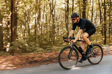 Side view of mature man with sporty body in protective helmet practising in cycling outdoors....