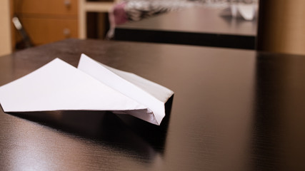 White paper plane on a black wooden table