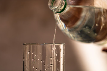 Pouring water from plastic bottle into a glass on blurred background. Selective focus and copy space