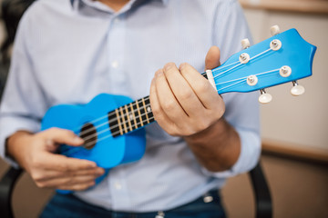 A man playing guitar ukulele in close up view