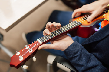 Obraz premium A man playing guitar ukulele in close up view