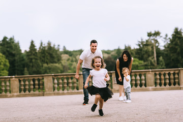 Handsome young father and beautiful mother in sunny summer nature playing with their cute small childrens