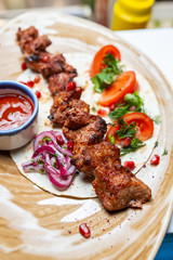 Shish kebab lies on pita bread with vegetables and sauce