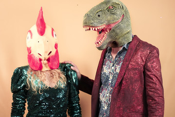 Couple wearing with t-rex dinosaur and chicken mask. Crazy friends having fun celebrating a party....