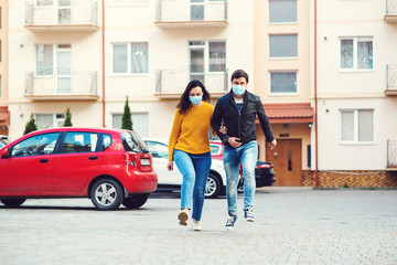 Fototapeta na wymiar Coronavirus epidemic. Young couple wearing face masks at street.