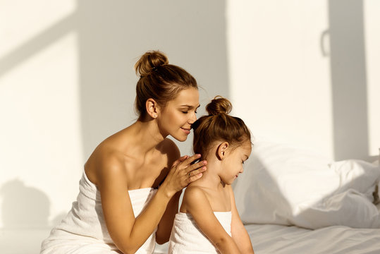 A young caucasian woman with his daughter on a bed at home in the morning, wearing in towel