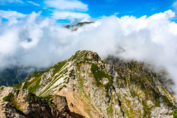 夏の北アルプス後立山連峰、唐松岳へ向かう八方尾根。雲の間に見える白馬岳