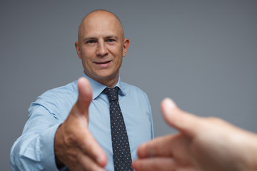 Satisfied businessman holds out his hand to secure a deal.