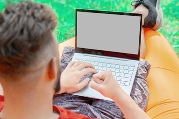 a man in a red T-shirt lies on an inflatable orange mattress on a summer day in nature and looks at the laptop screen