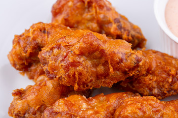 Fried legs and wings with breading, served with sauce and vegetables