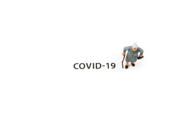 Old woman and coronavirus outbreak. Small figurine and text about Covid-19 on white background.