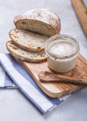 Fresh homemade bubbly sourdough starter, a fermented mixture of water and flour to use as leaven for bread baking, on wooden table