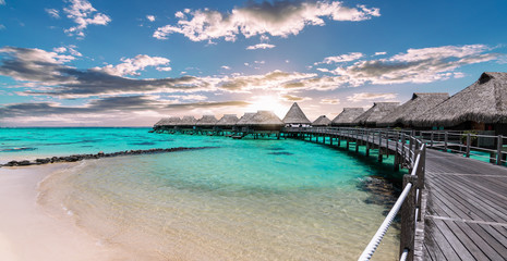 Scenic panoramic landscape view of  luxury overwater bungalows at the beach and lagoon during sunset in Moorea, French Polynesia. - obrazy, fototapety, plakaty