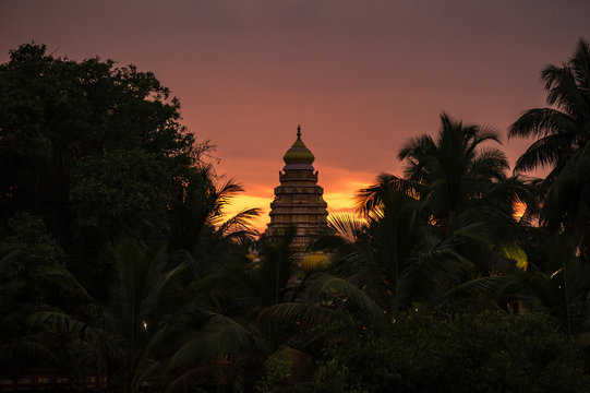 Hindu temple surrounded by palm trees during sunset