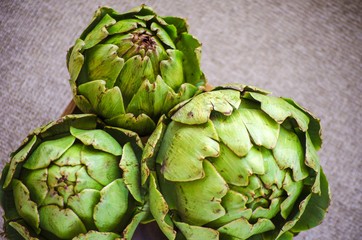 Fototapeta premium Artichokes close up. Artichoke flowers in rustic wooden bowl. Healthy eating concept, vegetable background, natural eco products. Selective focus image. Copy space.