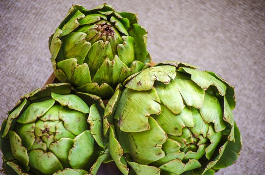 Artichokes close up. Artichoke flowers in rustic wooden bowl. Healthy eating concept, vegetable background, natural eco products. Selective focus image. Copy space.