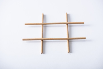 panoramic shot of grid made of paper pipes for tic tac toe game on white surface
