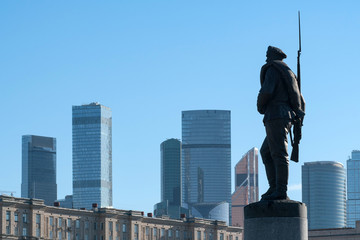 Soldier of Great War monument against old soviet residential house and skyscrapers of Moscow city. Moscow, Russia.