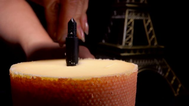 Girolle cheese scraper special knife cuts shavings from a top of hard parmezan cheese wheel on the background of the Eiffel Tower model