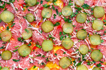 pizza preparation, selective focus. pizza with pepperoni sausage, salami cucumbers, spices, parsley, Basil, sauce. background texture