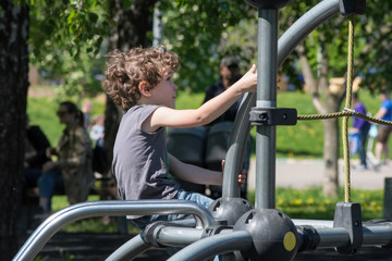 Fototapeta na wymiar Six-year-old boy plays on the playground in the city park.