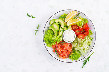 Salad of salted fish salmon, avocado, cherry tomatoes, cucumber, lettuce and cream cheese. Fish menu. Dietary menu. Seafood - salmon. Top view, overhead, flat lay