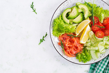 Salad of salted fish salmon, avocado, cherry tomatoes, cucumber, lettuce and lemon. Fish menu. Dietary menu. Seafood - salmon. Top view, overhead, flat lay