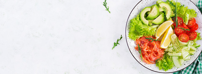 Salad of salted fish salmon, avocado, cherry tomatoes, cucumber, lettuce and lemon. Fish menu. Dietary menu. Seafood - salmon. Top view, overhead, banner