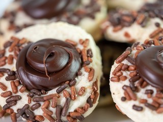 Thumbprint cookies with chocolate frosting and brown sprinkles piled up, delicious baked goods.