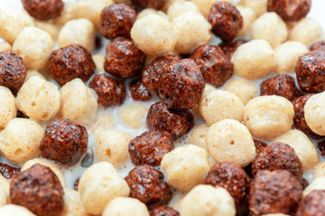 Breakfast cereal white chocolate balls close-up selective focus in milk background, texture