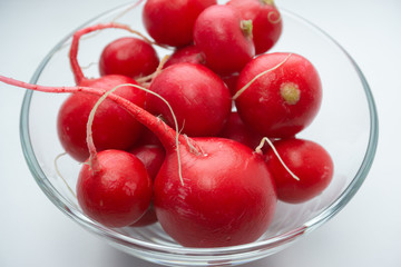 Red clean radishes in a glassy bowl top view on a white background. close-up, selective focus