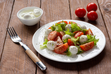 Salad with cherry tomatoes, lettuce, mozzarella and lemon-oil dressing