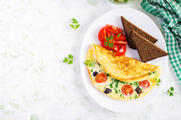 Breakfast. Omelette with tomatoes, black olives, cottage cheese and green herbs on white plate.  Frittata - italian omelet. Top view