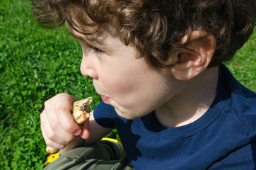 A cute curly boy eats pancake.