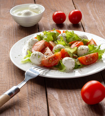 Salad with cherry tomatoes, lettuce, mozzarella and lemon-oil dressing