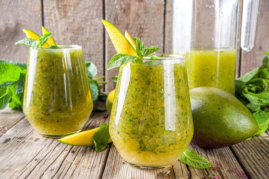 Summer unusual refreshing drink. Indian traditional salted lemonade aam panna (aam panha) cocktail, with mint and green mango. Indian mango mojito. On a wooden background with mango and mint
