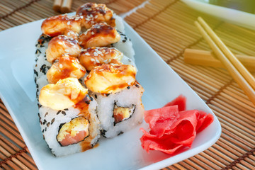Sushi on white plate close-up, macro avocado, cream cheese, sesame. Japan restaurant menu, fried sauce on top of ginger