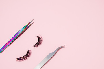 Set for eyelash extension on a pink background. Concept beauty beauty. False eyelashes and tweezers - obrazy, fototapety, plakaty