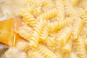 Boiling fusilli macaroni in a pot on an electric stove close up. Steam and Bubbling of hot water.