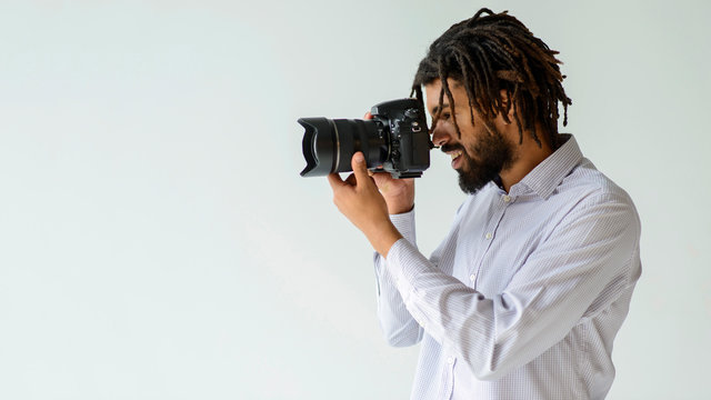 Medium shot man taking pictures. Black man in photography studio.