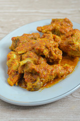 Ayam rica-rica in white plate. Indonesian food made from chicken and various seasonings. has a spicy taste. wooden background