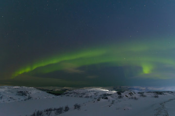 Aurora and stars in the sky .The rocks and ground are covered with snow.Arctic.