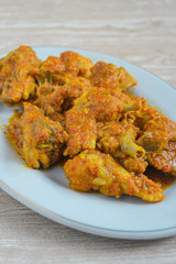 Ayam rica-rica in white plate. Indonesian food made from chicken and various seasonings. has a spicy taste. wooden background