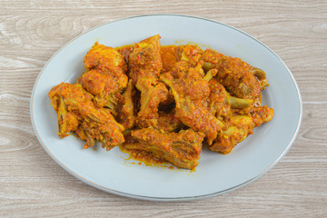 Ayam rica-rica in white plate. Indonesian food made from chicken and various seasonings. has a spicy taste. wooden background