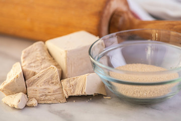 dried and fresh yeast on a white kitchen bacground with wooden rolling pin