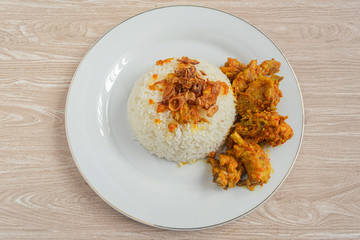 Nasi ayam rica-rica in white plate. Indonesian food made from chicken and various seasonings. has a spicy taste. wooden background