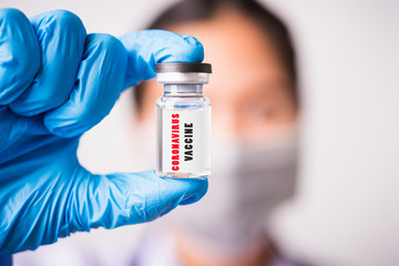 Obraz premium woman doctor or scientist wearing face mask protective in lab use hand finger hold vial vaccine bottle